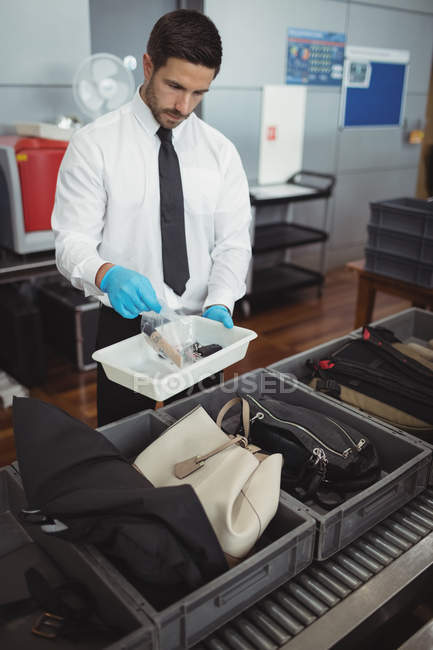 Security officer holding tray of liquid and keys in airport — Stock Photo