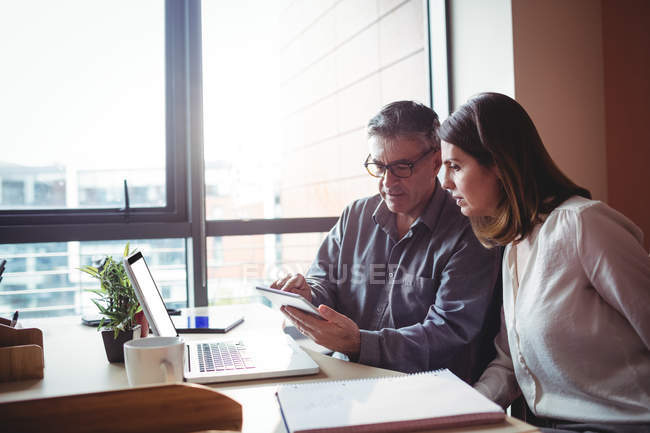 Мужчина и женщина обсуждают за цифровым планшетом в офисе — стоковое фото
