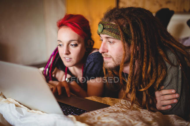 Jovem casal hipster usando laptop na cama em casa — Fotografia de Stock