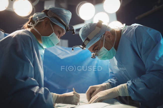 Two surgeons performing operation in operation room at hospital — Stock Photo