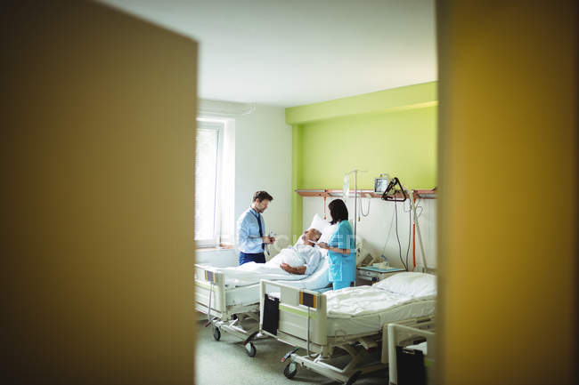 Médico y enfermera interactuando con el paciente en el hospital - foto de stock
