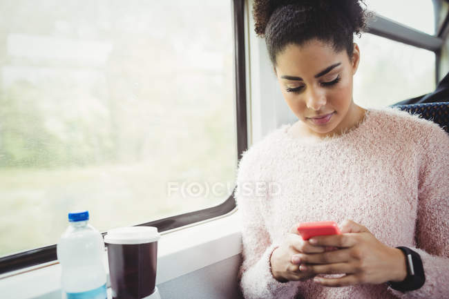Mujer usando el teléfono mientras está sentado en el tren - foto de stock