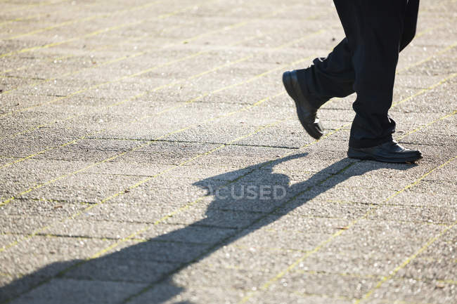 Niedriger Teil des Mannes, der bei Tageslicht auf der Straße läuft — Stockfoto