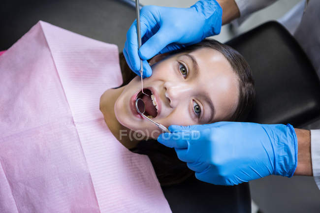 Стоматолог досліджує молодого пацієнта з інструментами в стоматологічній клініці — стокове фото
