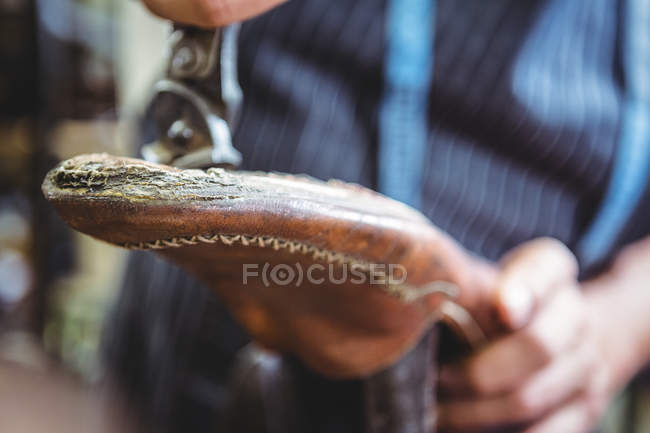 Close-up of shoemaker holding a shoe in workshop — Stock Photo
