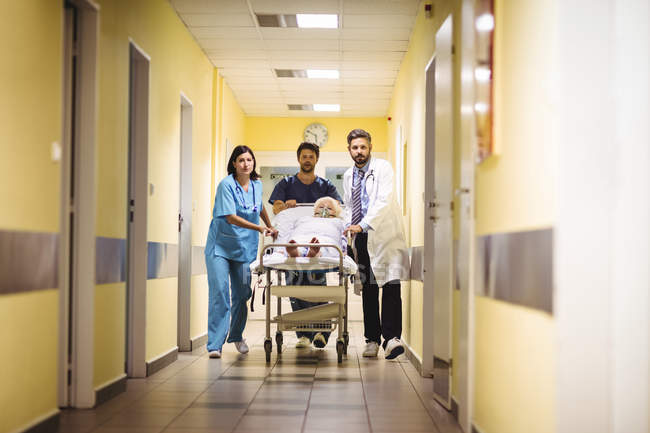 Arzt und Krankenschwester schieben Seniorin auf Trage in Krankenhausflur — Stockfoto