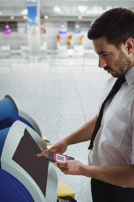 Viajero que utiliza la máquina de facturación de autoservicio en el aeropuerto - foto de stock