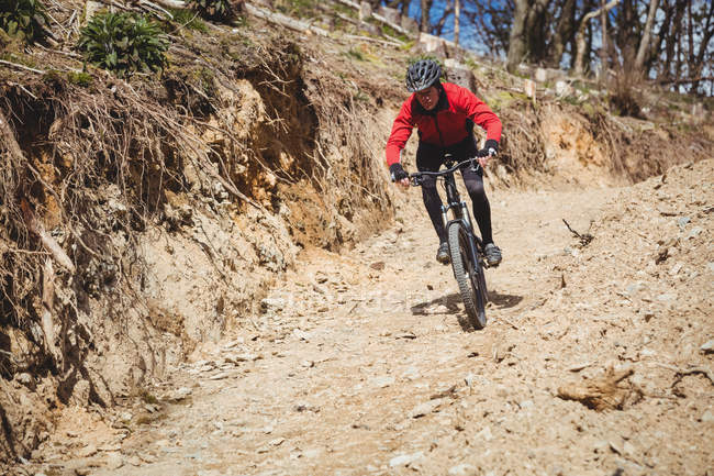 Front view of mountain biker riding on dirt road at mountain — Stock Photo