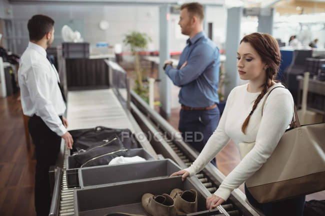 Frau steckt Schuhe für Sicherheitskontrolle am Flughafen in Tablett — Stockfoto