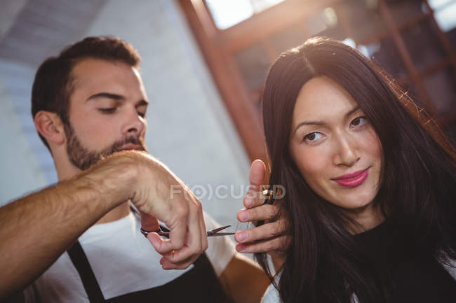 Female getting her hair trimmed with scissors in salon — Stock Photo