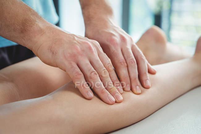 Immagine ritagliata del fisioterapista che somministra fisioterapia alla gamba della paziente in clinica — Foto stock