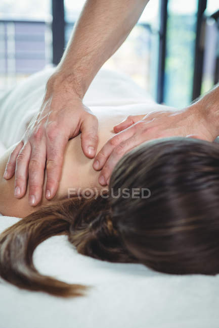 Fisioterapeuta que da fisioterapia a la espalda de una paciente en la clínica - foto de stock