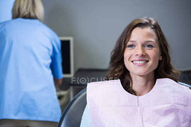 Paciente sonriente sentado en la silla del dentista en la clínica - foto de stock