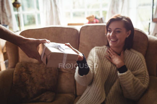 Homme femme surprenante avec cadeau dans le salon à la maison — Photo de stock