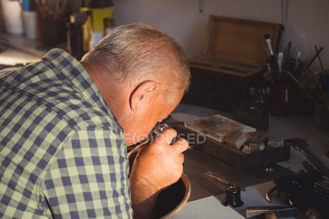 Goldschmied schaut durch Lupe in Werkstatt — Stockfoto