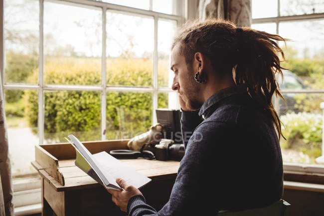 Hipster-Mann liest zu Hause Buch am Fenster — Stockfoto