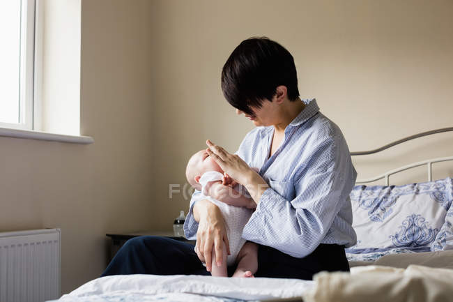 Mother sitting with baby in bedroom at home — Stock Photo