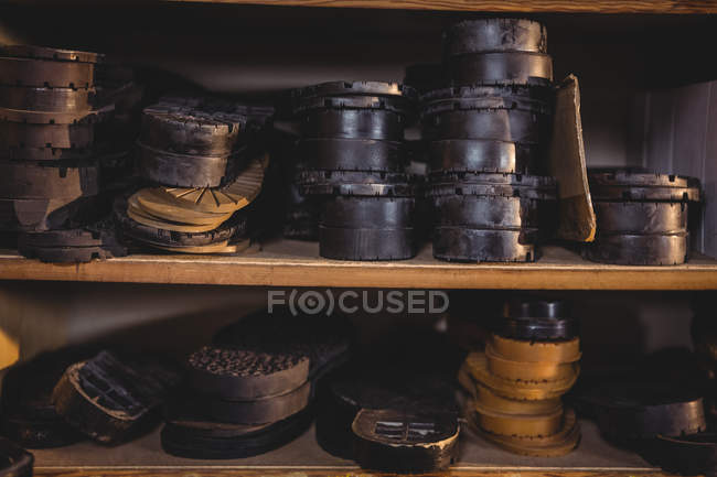 Montones de plantillas de zapatos de cuero en estantes en taller de calzado - foto de stock