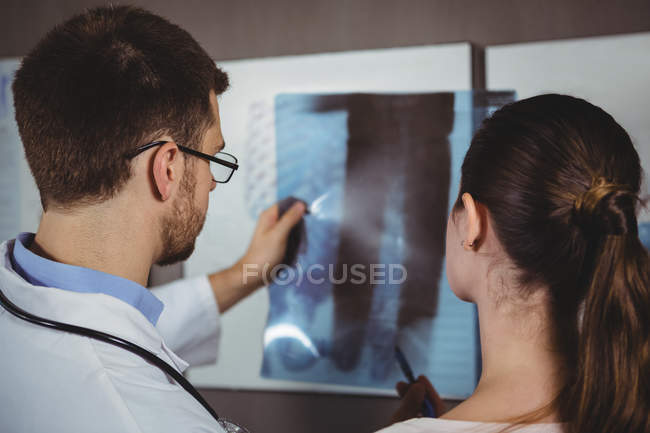 Fisioterapeuta explicando raio-X da coluna vertebral para paciente do sexo feminino na clínica — Fotografia de Stock