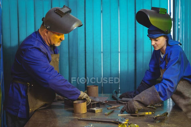 Мужские и женские сварщики работают вместе в мастерской — стоковое фото