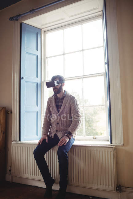 Young man using virtual glasses at home near window — Stock Photo