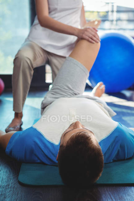 Fisioterapeuta dando fisioterapia ao joelho do paciente masculino na clínica — Fotografia de Stock