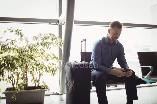 Empresario que usa teléfono móvil en la sala de espera en la terminal del aeropuerto — Stock Photo