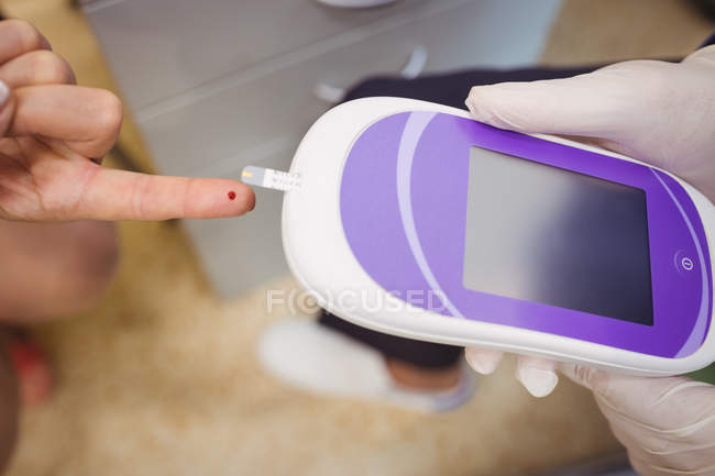 Nahaufnahme des Arztes, der den Zuckerspiegel eines Patienten mit Glukometer im Krankenhaus misst — Stockfoto