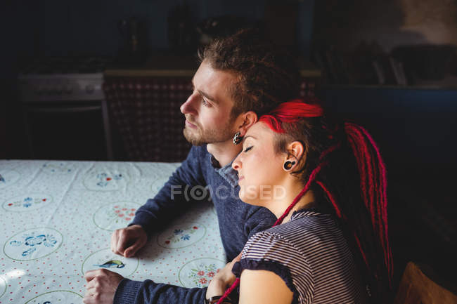 Pensativa pareja hipster sentado en la mesa en casa - foto de stock