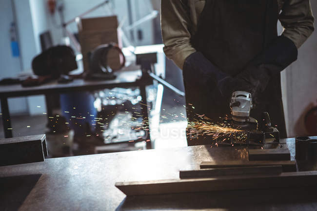 Обрізане зображення ріжучого металу зварювальника з електричним інструментом в майстерні — стокове фото
