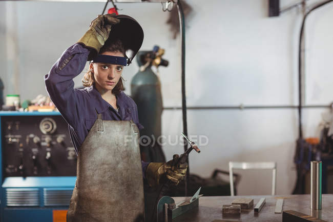 Schweißerin hält Schweißbrenner in Werkstatt — Stockfoto