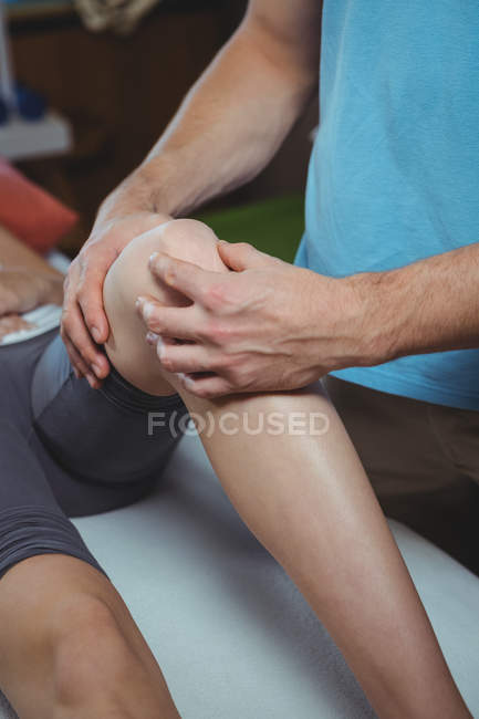 Обрізане зображення фізіотерапевта, що дає фізичну терапію колінному суглобу пацієнта в клініці — стокове фото