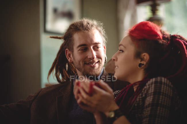 Sorridente giovane coppia seduta sul divano a casa — Foto stock