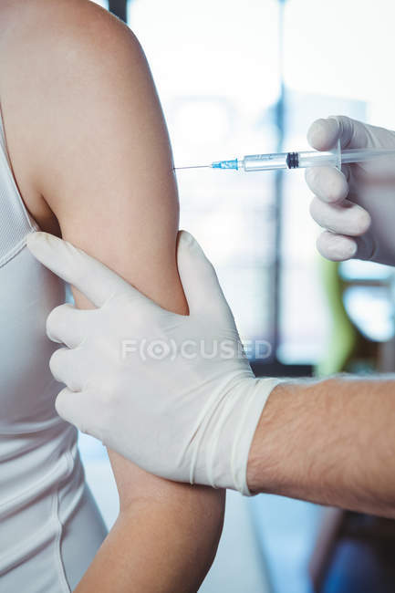 Imagen recortada del terapeuta masculino inyectando paciente femenino en la clínica - foto de stock