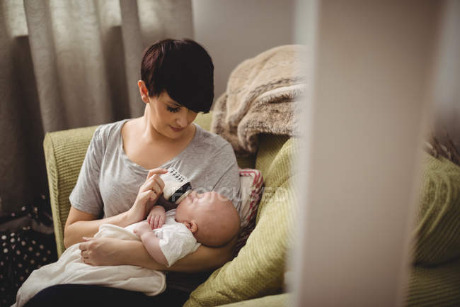Mother feeding her baby in living room at home — Stock Photo