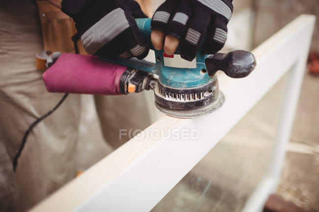 Imagem cortada de Carpenter polimento moldura de madeira com máquina de polir — Fotografia de Stock
