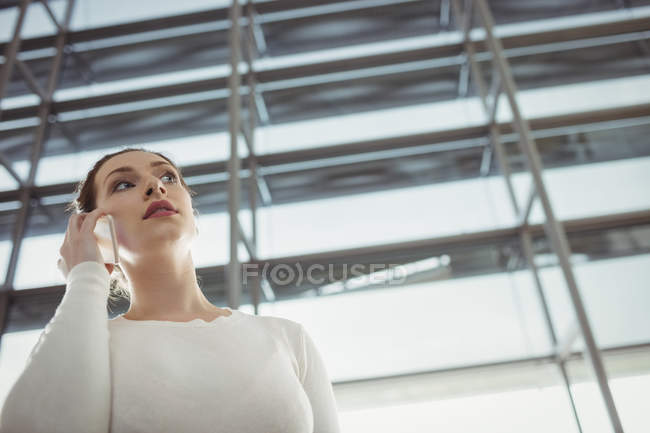Woman talking on mobile phone in waiting area at airport terminal — Stock Photo