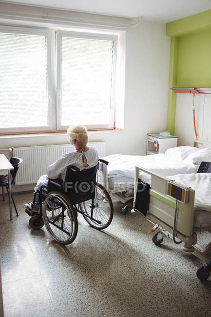 Mujer mayor sentada en silla de ruedas en el hospital - foto de stock