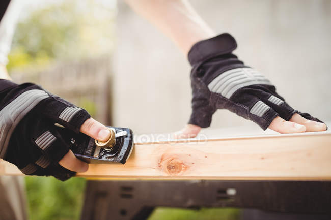 Cropped image of carpenter sharpening chisel on stone — Stock Photo