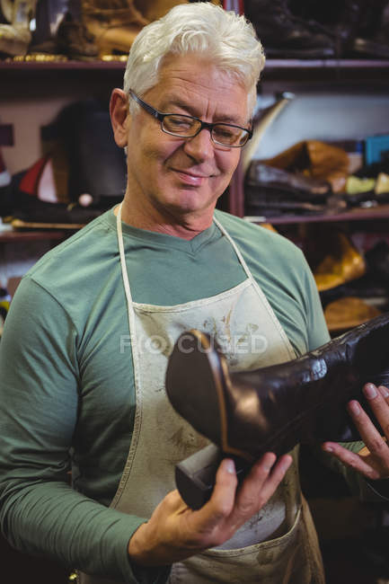 Schuhmacher begutachtet Schuh in Werkstatt — Stockfoto