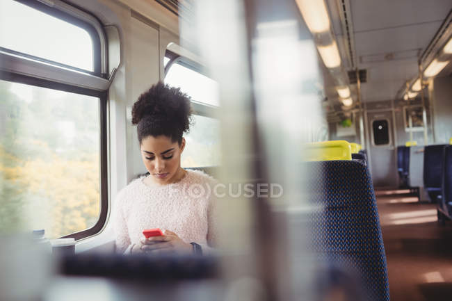 Bella donna che utilizza il telefono cellulare mentre seduto in treno — Foto stock