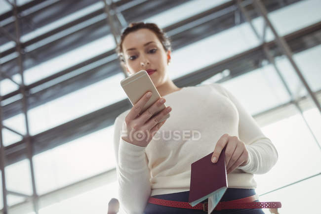 Joven pasajera usando teléfono móvil en terminal aeroportuaria - foto de stock