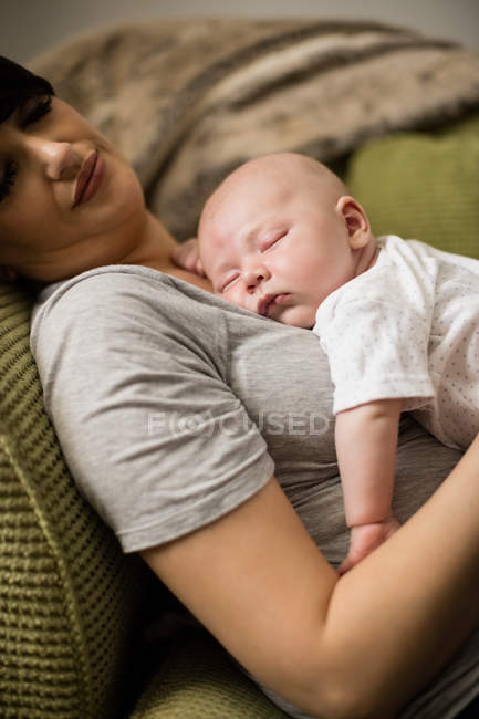 Mãe e bebê dormindo no sofá na sala de estar em casa — Fotografia de Stock