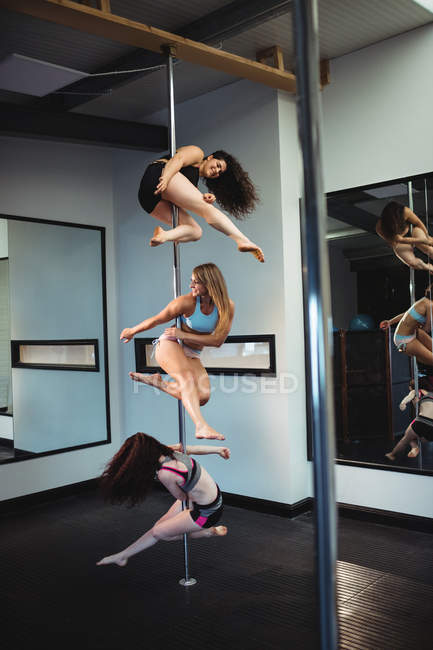 Pole dancers practicing pole dance in fitness studio — Stock Photo