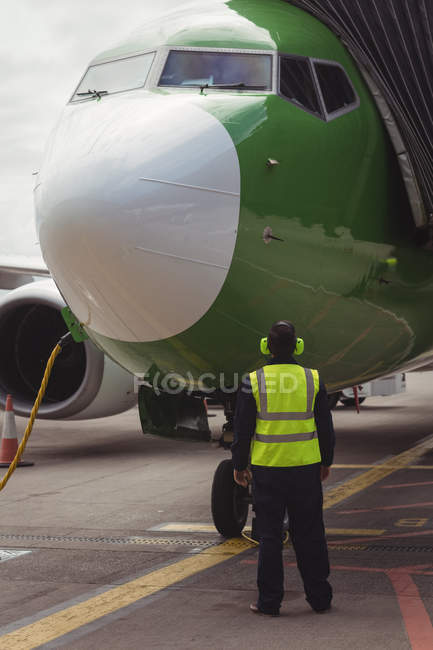 Rear view of airport ground crew worker directing airplane on runway — Stock Photo