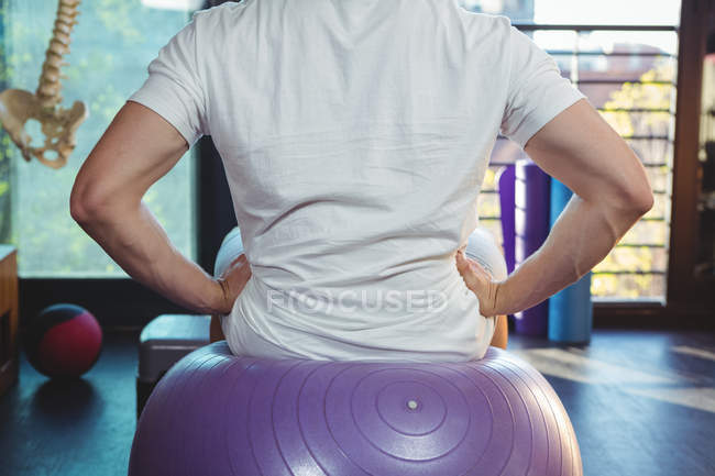 Back view of Male patient sitting on exercise ball in the clinic — Stock Photo