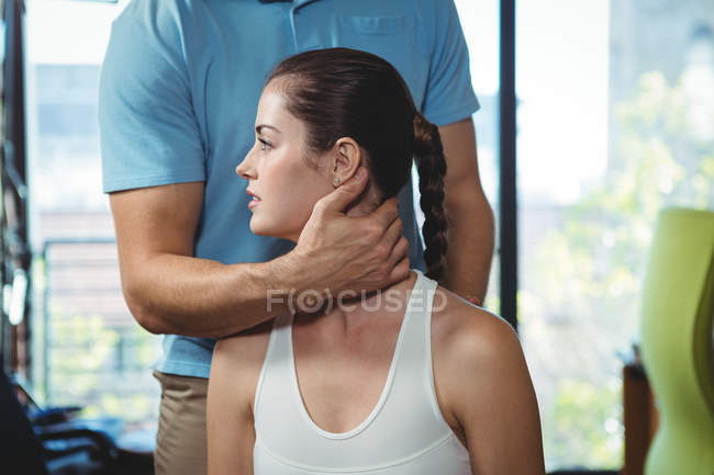 Fisioterapeuta examinando cuello de paciente femenina en clínica - foto de stock