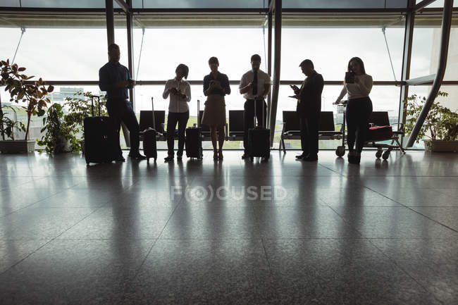 Business people using mobile phone in waiting area at airport terminal — Stock Photo
