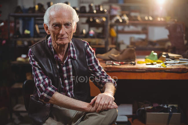 Портрет уверенного сапожника сидящего в мастерской — стоковое фото