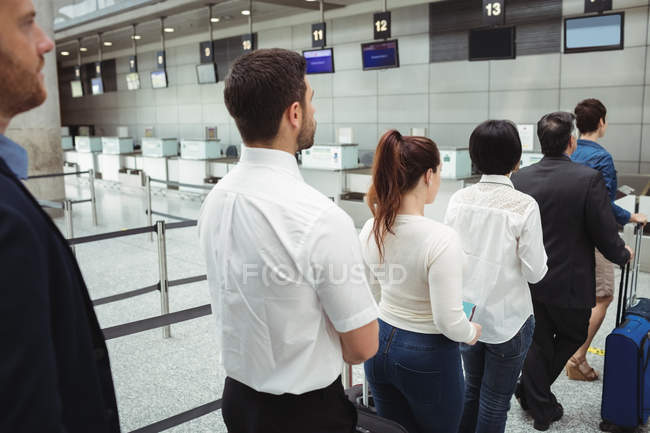 Пасажири чекають черги на стійці реєстрації з багажем всередині терміналу аеропорту — стокове фото